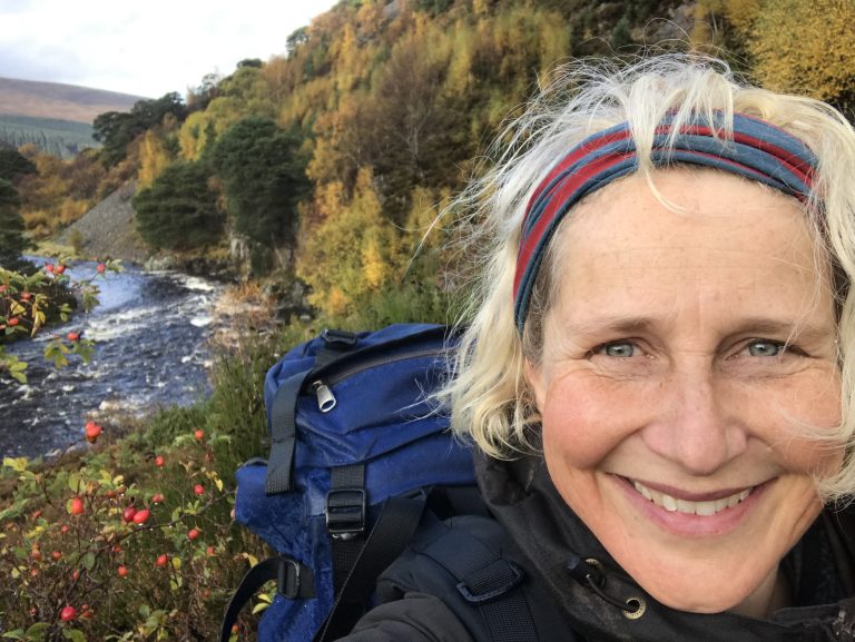 A female looks at the camera and has a river behind.