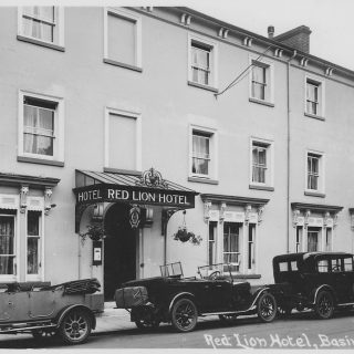 An old photograph of the Red Lion Hotel in Basingstoke. A black and white image of a three storey building on a street.