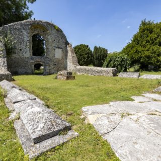 Large stone ruins with green grass growing inbetween against a bright blue sky